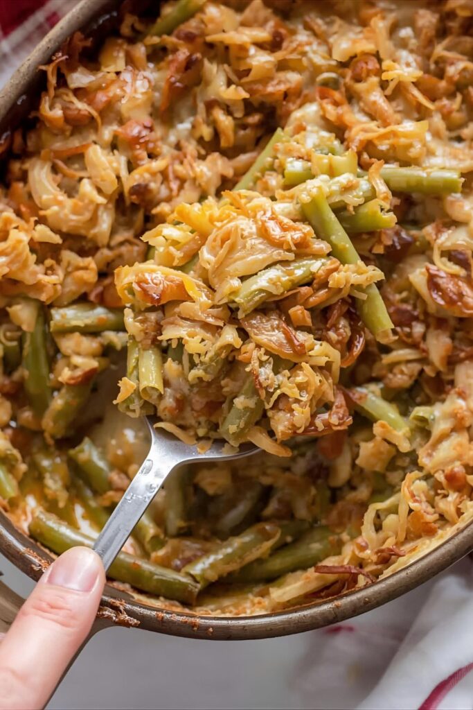  A close-up shot of a scoop of homemade green bean casserole being taken from a baking dish.