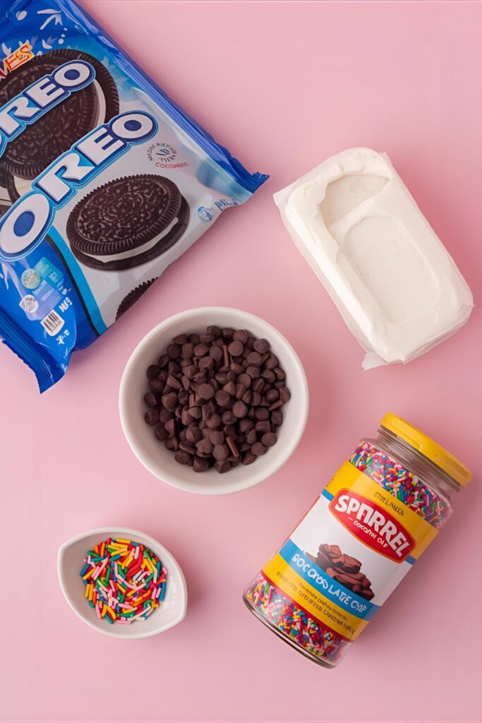 A flat lay of the 5 core ingredients for Oreo truffles: a package of Oreos, cream cheese, chocolate chips, coconut oil, and sprinkles.