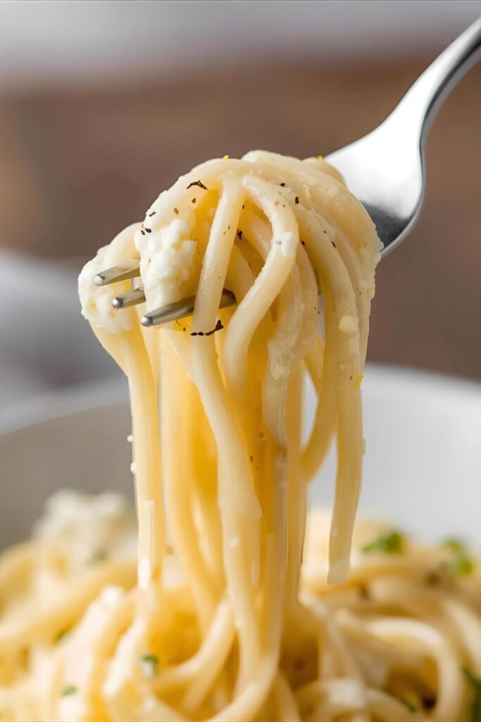 A close-up of a fork twirling a bite of creamy lemon ricotta pasta, showing the luscious sauce.