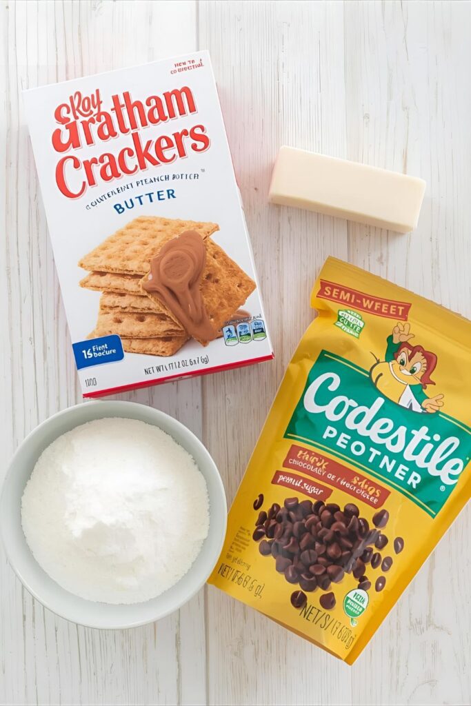  A flat lay of the ingredients for chocolate peanut butter bars, including graham crackers, peanut butter, butter, and chocolate chips.