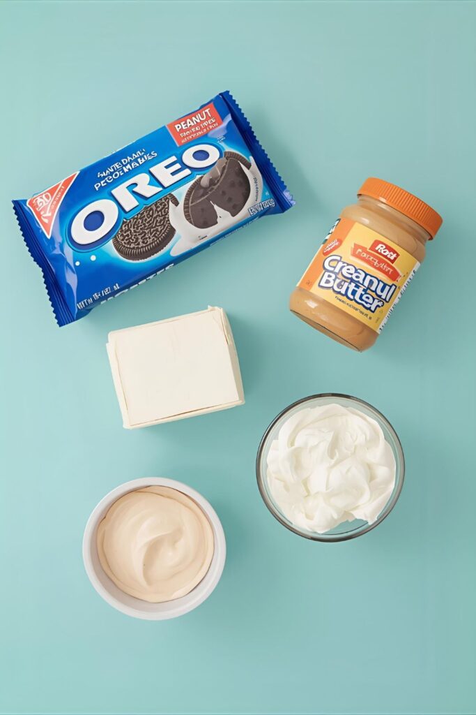A flat lay of the ingredients for a no-bake peanut butter pie, including Oreos, cream cheese, peanut butter, and whipped topping.