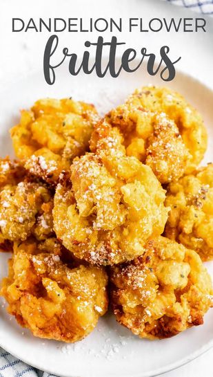 A pile of golden-brown, crispy dandelion flower fritters dusted with powdered sugar, served on a white plate with a sprig of mint. Text overlay reads: DANDELION FLOWER FRITTERS