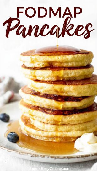 A high stack of golden-brown FODMAP pancakes drizzled with maple syrup and topped with fresh blueberries, with the text overlay "FODMAP PANCAKES".