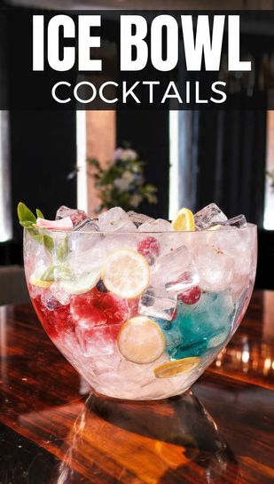A large, crystal-clear ice bowl centerpiece filled with a pink punch, featuring frozen citrus slices and berries suspended in the ice wall. Text overlay reads: ICE BOWL COCKTAILS
