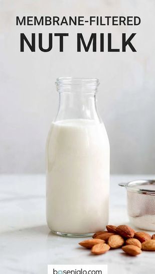 A clear glass bottle of creamy white nut milk next to a pile of raw almonds, emphasizing the clean, ultra-smooth texture. Text overlay reads: MEMBRANE-FILTERED NUT MILK