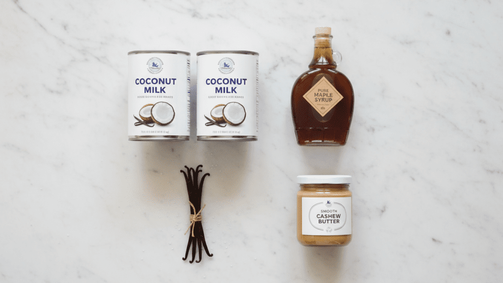 A collage of coconut milk cans, maple syrup, cashew butter, and vanilla beans.