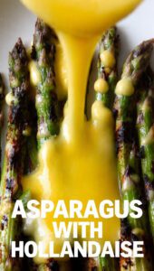 A close-up of vibrant green asparagus with creamy yellow hollandaise sauce drizzled over the tips.