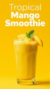 A tall glass of vibrant orange tropical mango smoothie with a straw and mint on top with text overlay "Tropical Mango Smoothie".